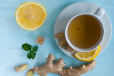 Mavi ahşap masada limonlu, zencefilli, nane ve kahverengi şekerli beyaz çay.