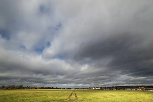 Big dark storm clouds looming over a small village in the distance — Stock Photo, Image