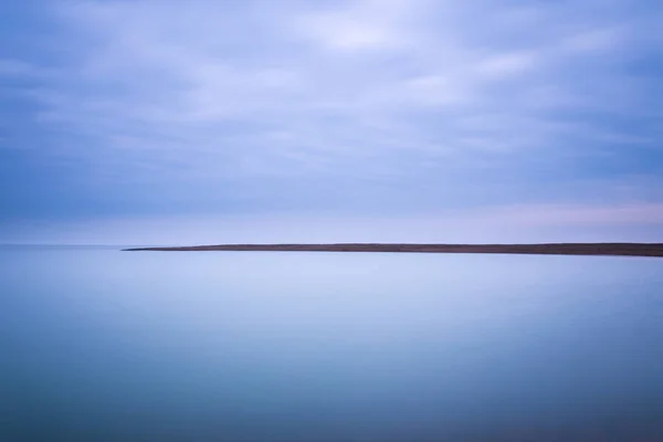 Una lunga esposizione delle nuvole e dell'acqua a Shingle Street nel Suffolk — Foto Stock