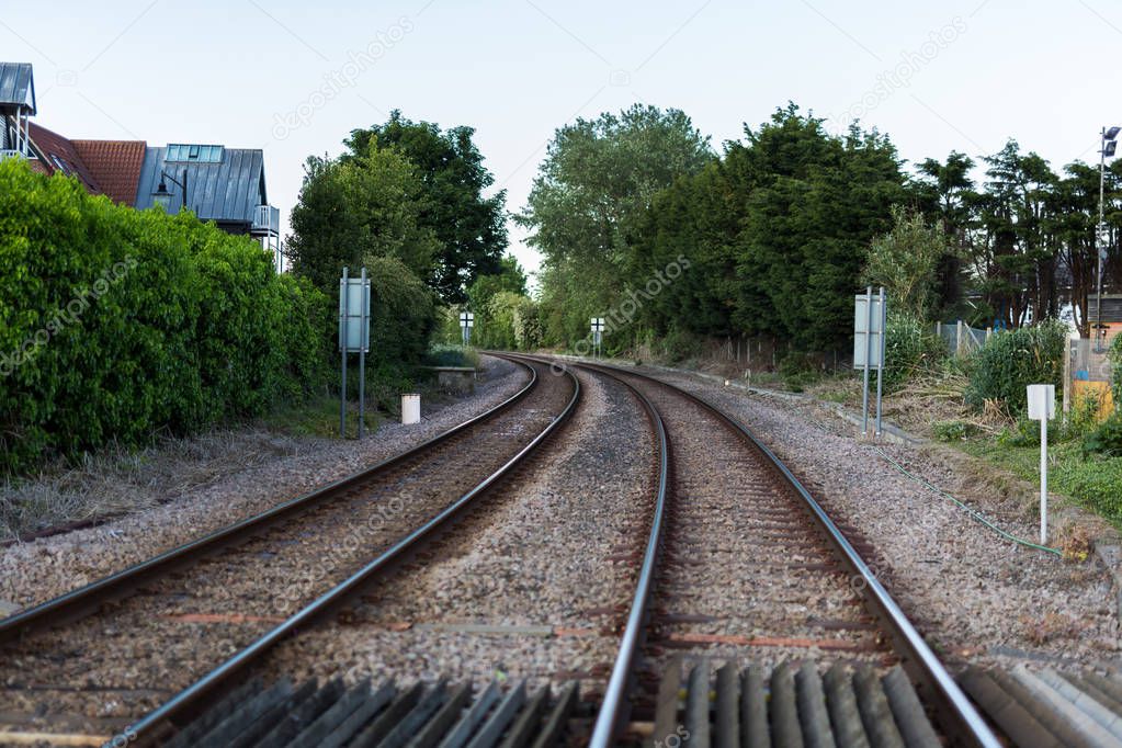 An empty train track, there are 2 tracks leading to a point on the horizon in rural countryside
