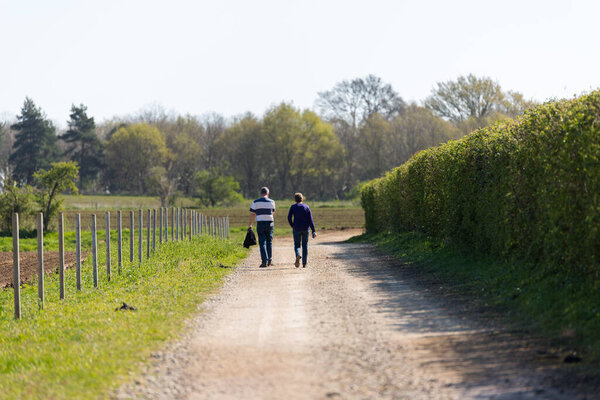 A middle aged couple taking a walk through the rural countryside on a bright and sunny day