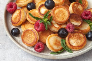 İçinde ahududu, nane ve böğürtlenli mini krep gevreği olan bir kase.