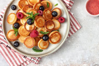 İçinde ahududu, nane ve böğürtlenli mini krep gevreği olan bir kase.