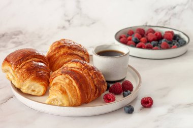 Taze kruvasan ve olgun böğürtlenli lezzetli bir kahvaltı.