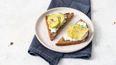 Süzme peynir ve avokadoyla sağlıklı çavdar tostu.