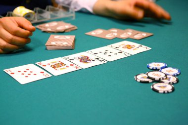 Poker masasında kartlar, jetonlar, eller, yığın bir arada.