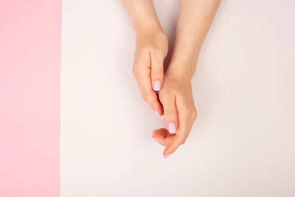 Manos con manicura sobre un fondo combinado doble rosa y blanco con lugar para el texto. Puesta plana — Foto de Stock