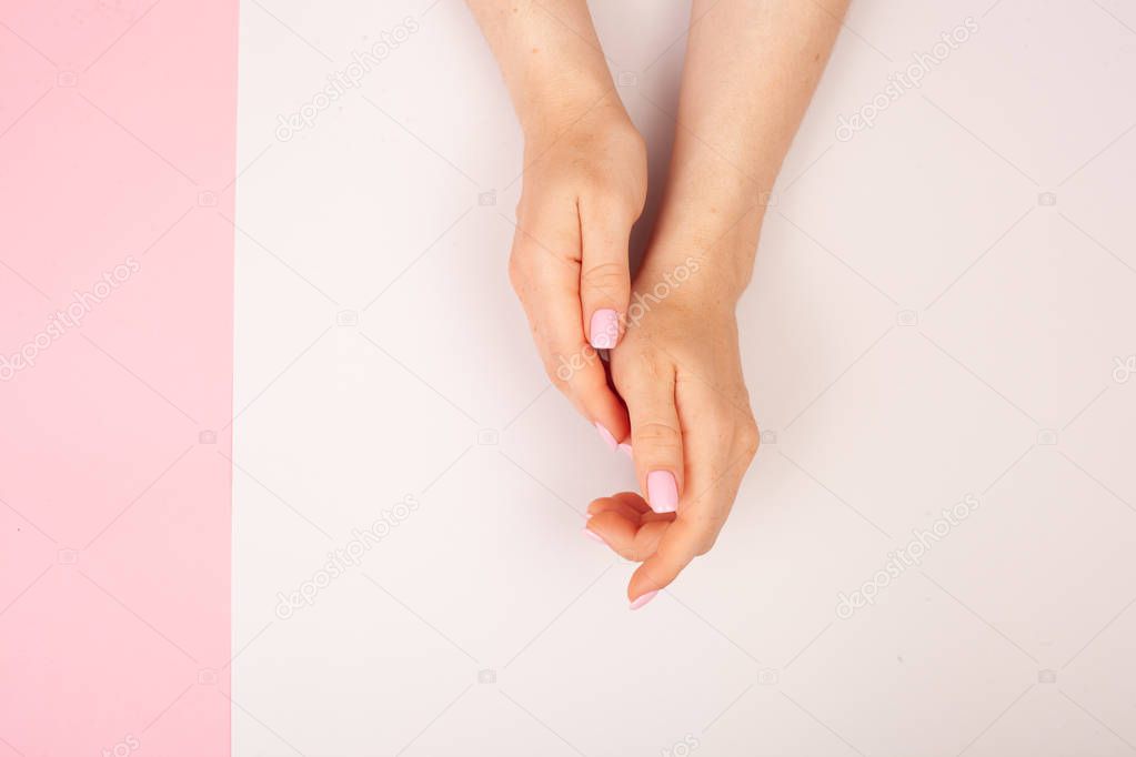 Hands with manicure on a combined double pink and white background with place for text. Flat lay