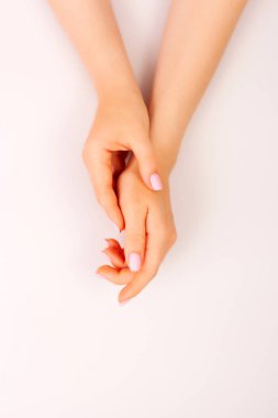 Pembe arka plan karşı çivi üzerinde manikür ile genç bir kadının elleri