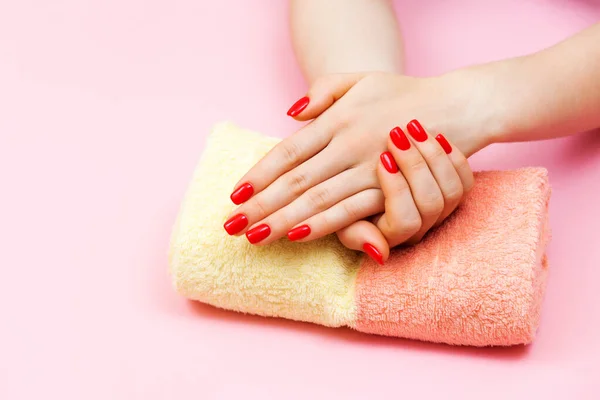 Nails design. Hands with bright trendy red manicure on pink background.