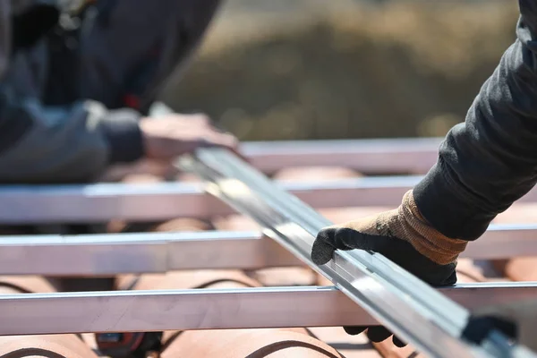 Los trabajadores de la construcción que instalan infraestructura metálica para paneles solares fotovoltaicos de energía alternativa en los techos —  Fotos de Stock