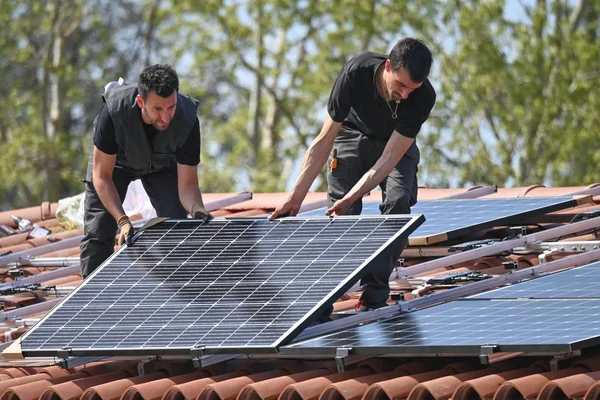 在住宅屋顶的金属基础设施上安装太阳能电池板的工人 — 图库照片