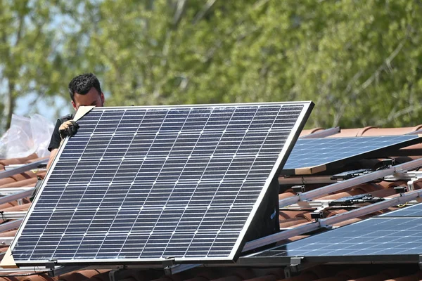 İkamet binasının çatısına metal altyapı üzerine güneş panelleri kuran İşçi