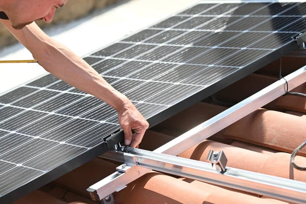 İkamet binasının çatısına metal altyapı üzerine güneş panelleri kuran işçiler