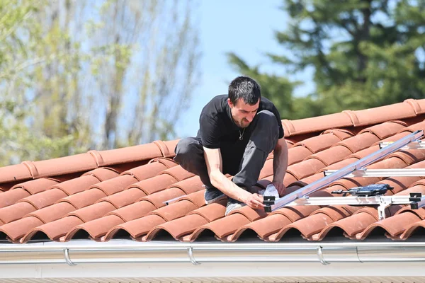 Bireysel evlerin çatısına güneş paneli kurmak için yapısal elementleri ölçen inşaat işçisi