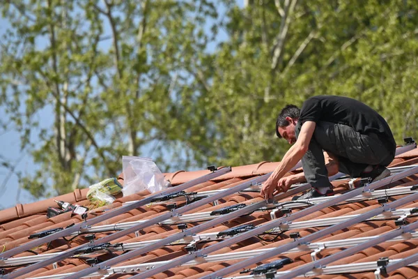 Bina işçisi bireysel evin çatısına güneş paneli kuruyor.