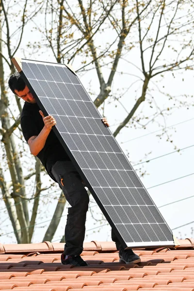 Genç teknisyen özel araçlar ile yeni ev çatısına alternatif enerji fotovoltaik güneş panelleri yükleme