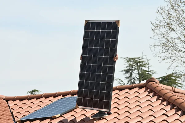 Young technician installing alternative energy photovoltaic solar panels on new house roof  with specialized tools