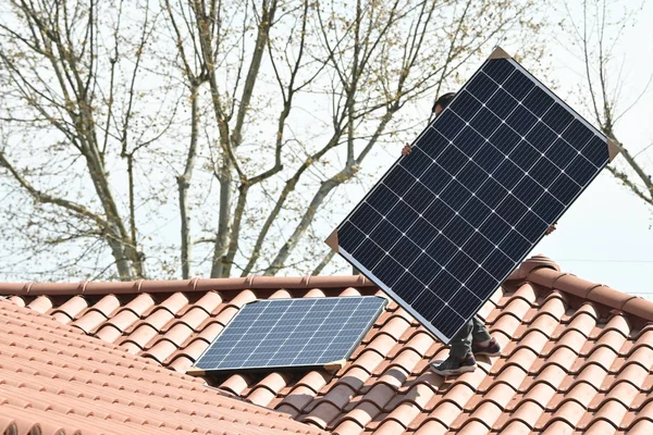 Young technician installing alternative energy photovoltaic solar panels on new house roof  with specialized tools