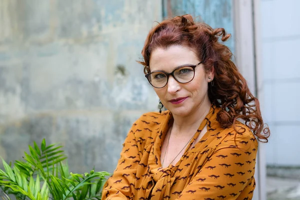 Dışarıda kızıl saçlı, gözlüklü, çekici, yaşlı bir kadının yakın plan portresi. 