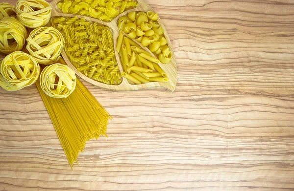 Makaron gniazda spaghetti przegrzebki linguini penne tagliatelle fusilli spirale. — Zdjęcie stockowe