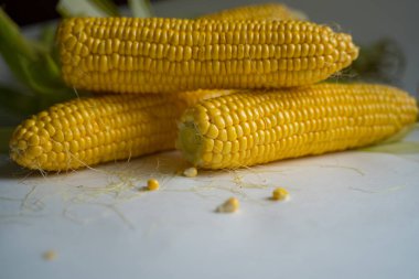 yeşil yaprakları olgun sarı mısır açık kulakları beyaz bir masa üzerinde yalan