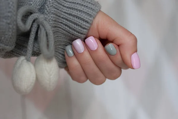 The pastel color manicure with the knitted sleeve of a brown sweater