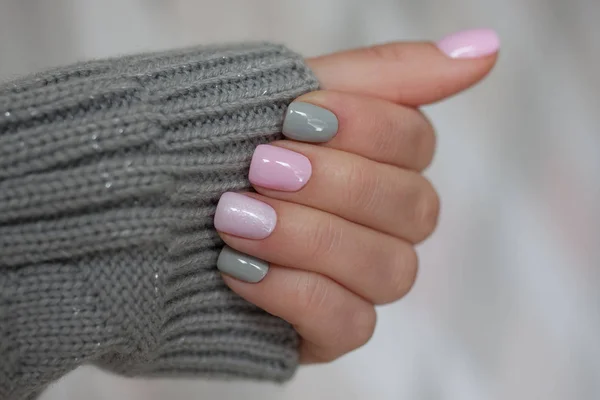 The pastel color manicure with the knitted sleeve of a brown sweater