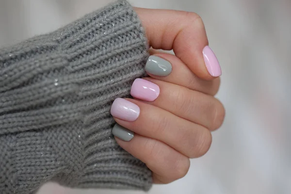 The pastel color manicure with the knitted sleeve of a brown sweater