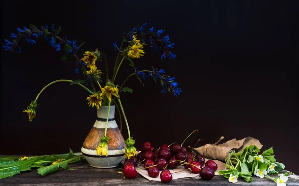 Cherry and wildflowers on a wooden craft table after rain — Stock Photo, Image