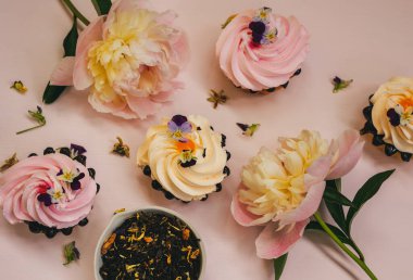 Pembe şakayıklar, kremalı kekler ve çiçek çayı.