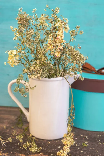 Fleurs sauvages dans une cruche blanche et une boîte cadeau sur une table rustique en bois — Photo