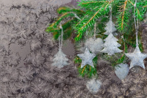 Kerstboom tak met kerstversiering door een bevroren raam met vorst — Stockfoto