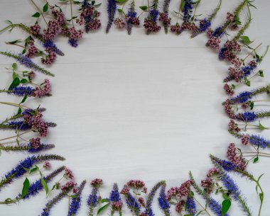 Gri ahşap yüzeyde mavi ve yaban çiçeklerinden yapılmış çerçeve