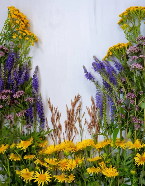 Arrangement de fleurs sauvages jaunes et bleues sur une surface en bois — Photo