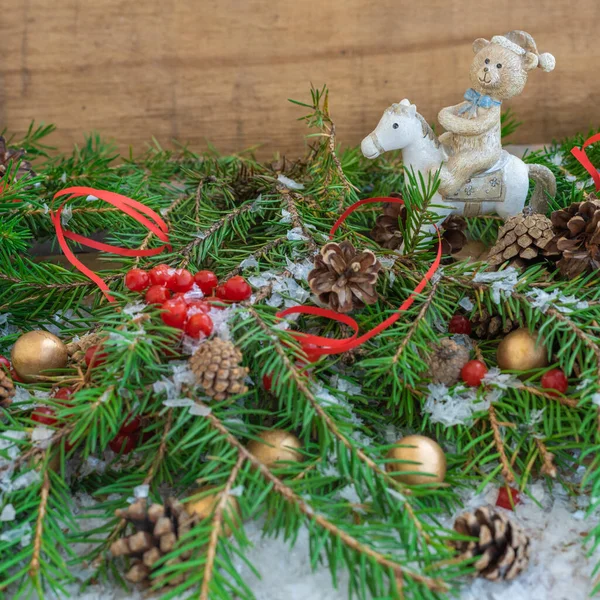 Christmas composition with fir branches, cones, berries and a toy - a bear on a horse — Stock Photo, Image