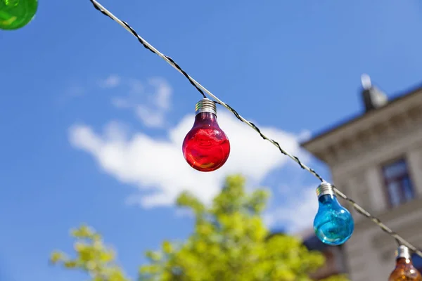 red light bulb on a wire with other lamps