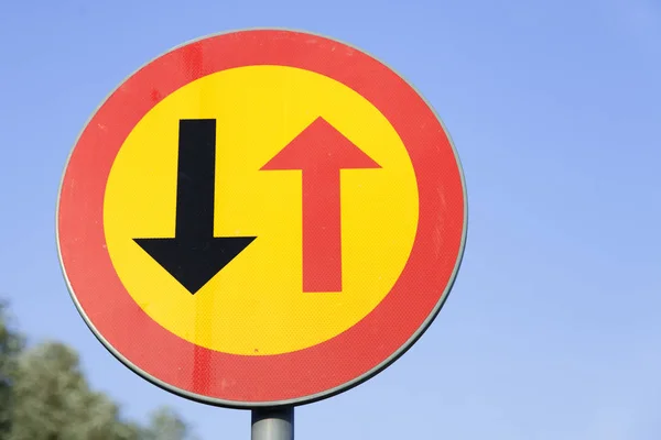 traffic sign with red and black arrow on yellow background