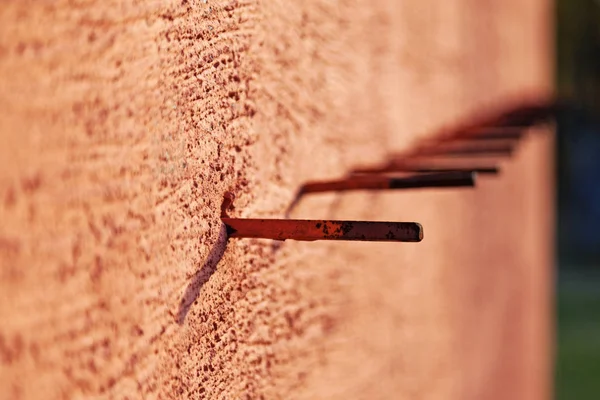 Une rangée de bâtons métalliques sortant du mur de béton orange — Photo