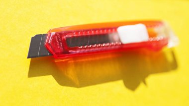 Sarı arka planda keskin pembe bir halı bıçağı var.