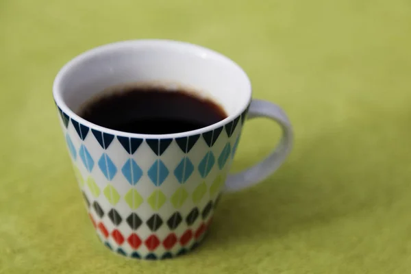 Hete koffie in mooie beker staan op groene picknick stof — Stockfoto