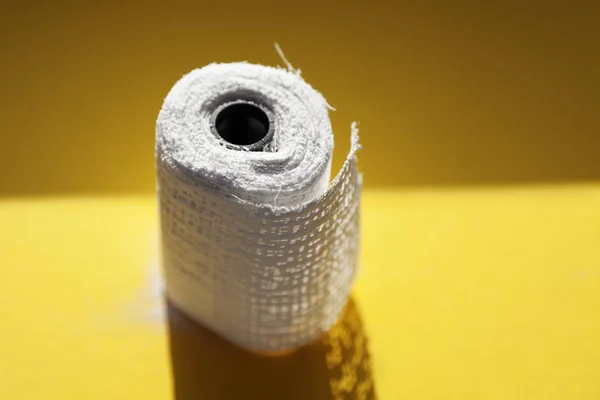 Un rollo de banda de yeso sobre fondo amarillo al sol — Foto de Stock