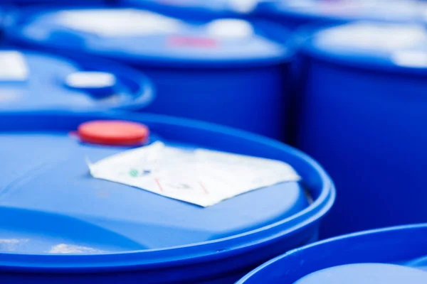 Arka planda bulanıklık ve yakın planda zehir içeren mavi plastik variller.