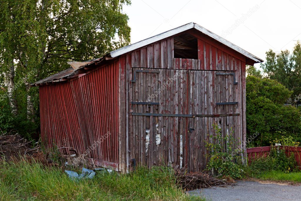 an old red wooden shed that is falling apart