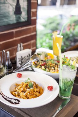 Salata ve taze içeceklerle servis edilen İtalyan makarnası