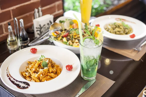 A table of Italian pasta served with salad and fresh drinks