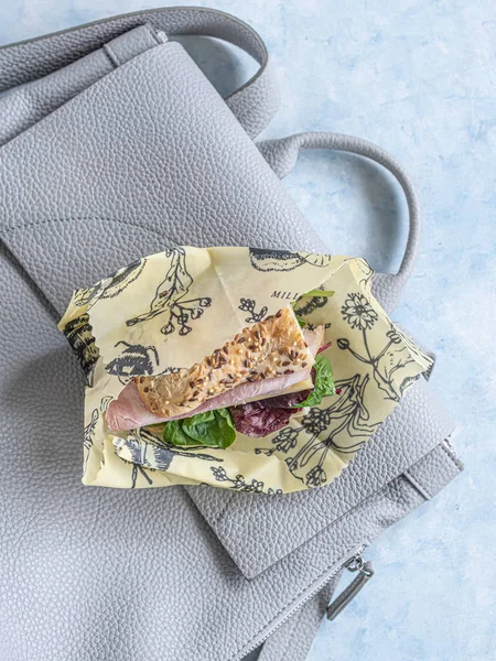 Colourful sandwich placed on a stylish grey back, wrapped in a beautiful beewax wrap, zero waste, no foil needed, environmental friendly, pack your lunch, no waste — Stock Photo, Image