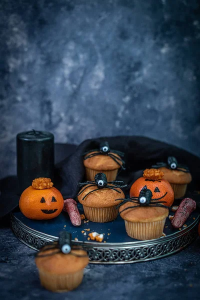 Muffins de Halloween, aranhas, dedos sangrentos e laranjas em uma bandeja em um fundo azul escuro, enferrujado, mal-humorado, assustador, assustador ideias de assar halloween Fotos De Bancos De Imagens