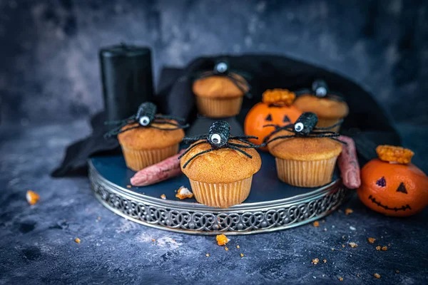 Muffins de Halloween, aranhas, dedos sangrentos e laranjas em uma bandeja em um fundo azul escuro, enferrujado, mal-humorado, assustador, assustador ideias de assar halloween Imagens De Bancos De Imagens Sem Royalties