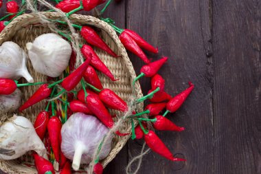 Biber ve sarımsak ahşap bir arka plan üzerinde hasır bir kapta